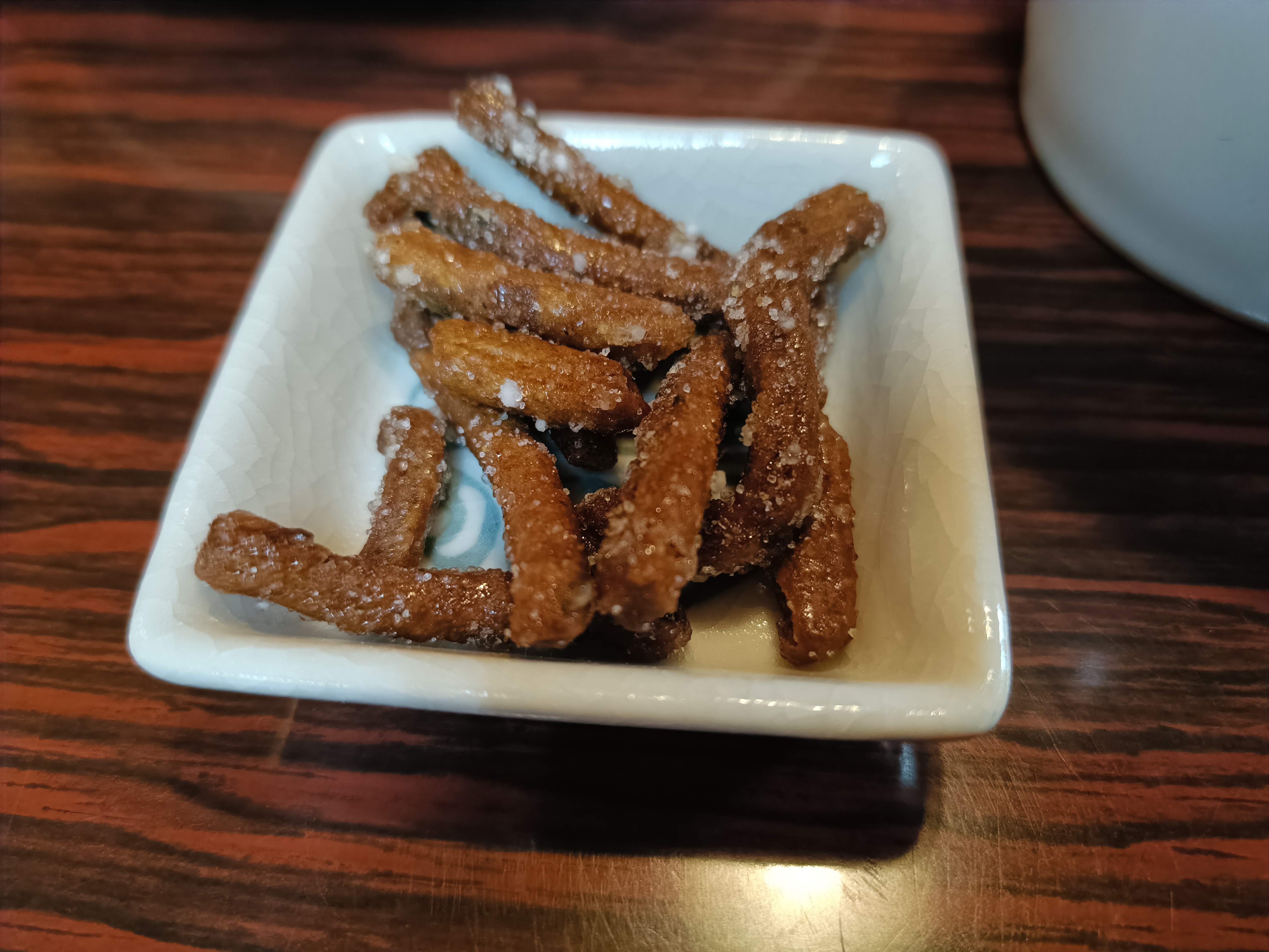 白磁の角皿に盛られた、黒糖蜜をまとったかりん堂の手揚げかりんとう